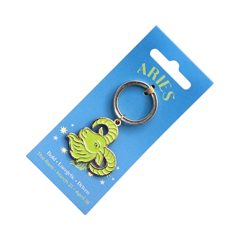 A green Aries zodiac symbol keychain with a silver split ring, attached to a blue cardboard hanger card with 'ARIES' printed in gold.