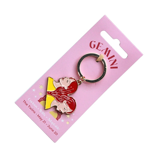 A Gemini-themed keychain featuring two cartoon twin characters in red and yellow, attached to a black split ring and mounted on a pink card labeled GEMINI.