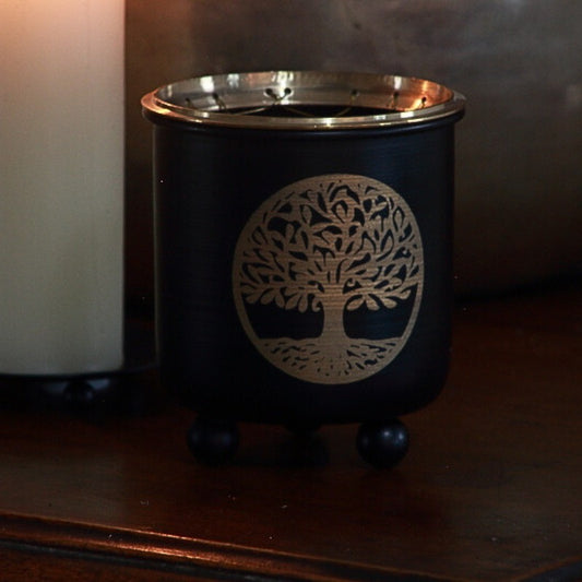 Black and gold incense charcoal burner  with a tree pattern on front on wooden table 