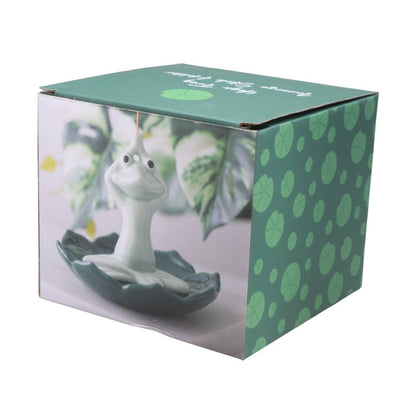 packing box featuring a green frog sitting cross legged on lily pad holding hands above head