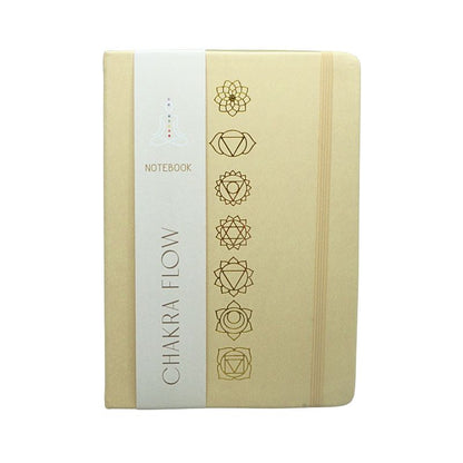 linen cover diary with the chakra symbols printed in gold on the cover. Gold edged pages and a tag with the words "Chakra Flow" and "Notebook" covering it.