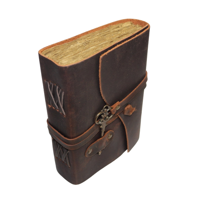 Antique style brown leather journal with a skeleton key on leather band that wraps around to close the cover. Inside contains plain "antiqued" pages  Spine has laced leather across it.