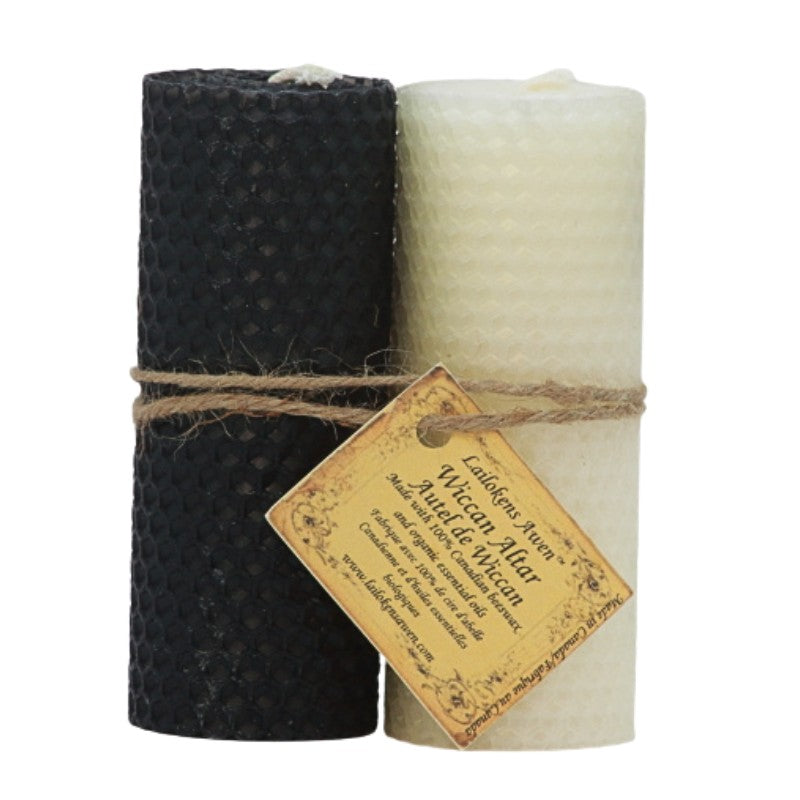 two rolled beeswax candles, one white and one black, wrapped in twine with a distressed label