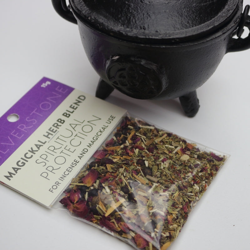 magickal herb blend packet for spiritual protection sitting in front of a black cauldron
