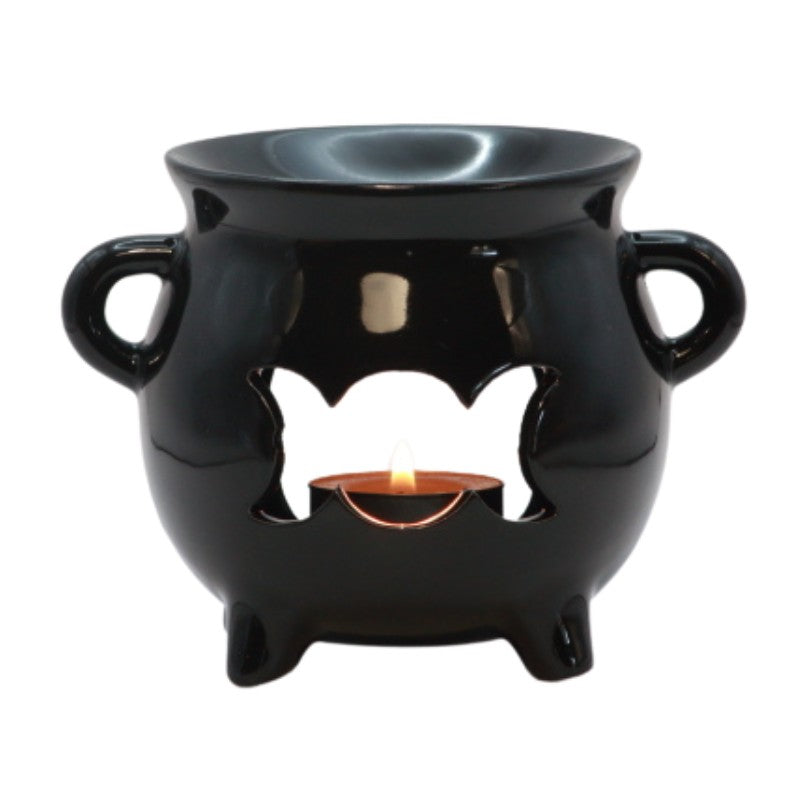 black ceramic cauldron oil burner with a triple moon shape cut out on the front and a beeswax tealight candle in the centre