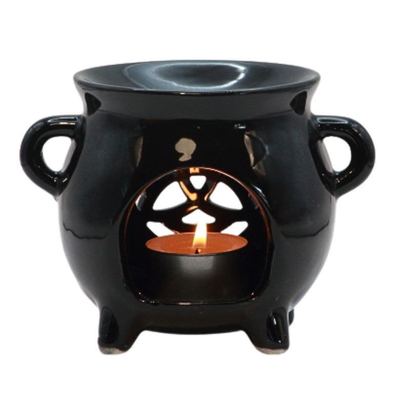 black ceramic cauldron oil burner with a triquetra shape cut out on the front and a beeswax tealight candle in the centre