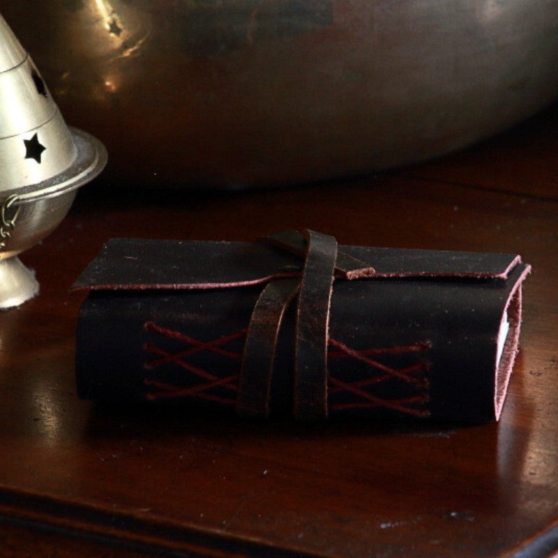 Oiled leather journal with a leather strap on wooden table