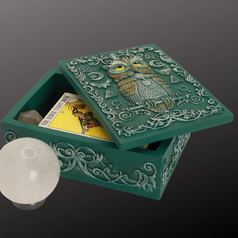 turquoise tarot and jewellery box with an owl and sacred symbols on the lid. Inside it is a pocket rider waite tarot deck and crystal point. Next to the box is a clear crystal ball