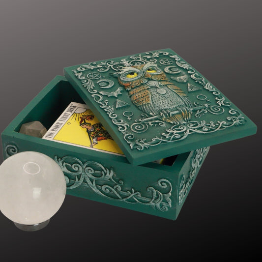 turquoise tarot and jewellery box with an owl and sacred symbols on the lid. Inside it is a pocket rider waite tarot deck and crystal point. Next to the box is a clear crystal ball