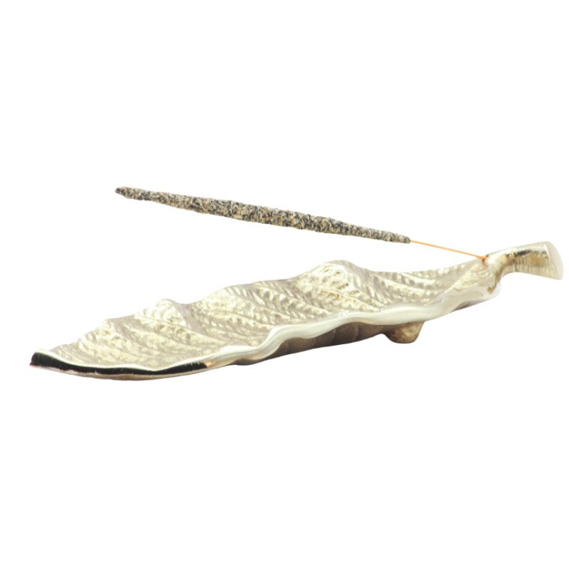 gold incense holder in the shape of a leaf holding a natural incense stick