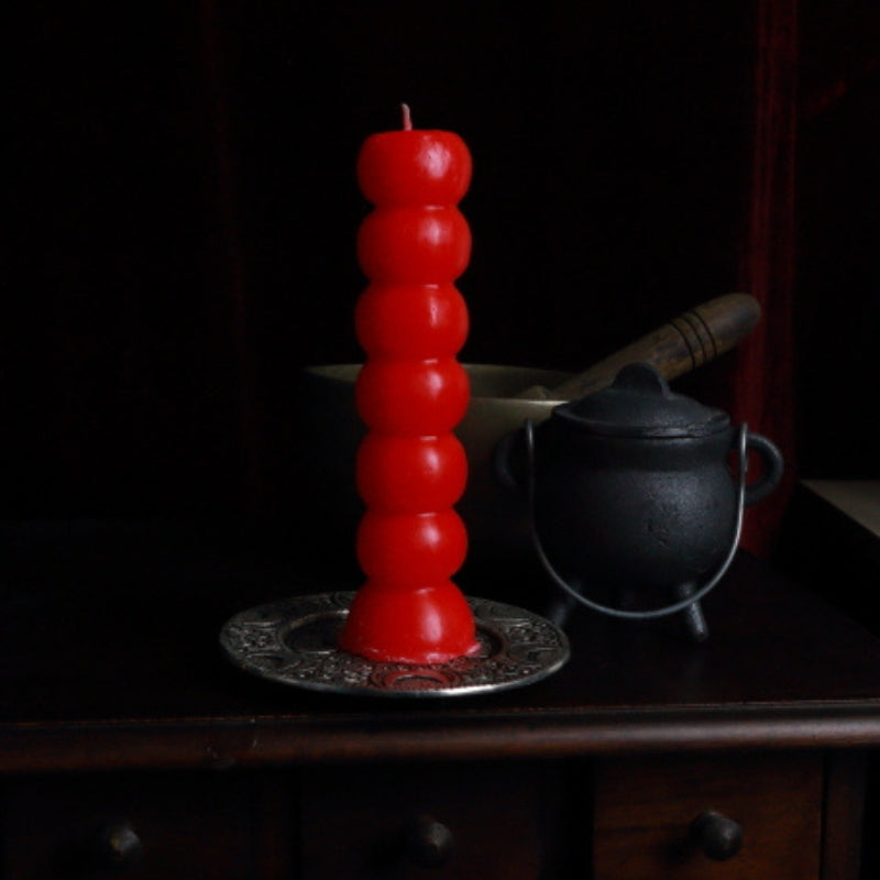 red 7 knob candle on an apothecary cabinet in front of a singing bowl and cauldron