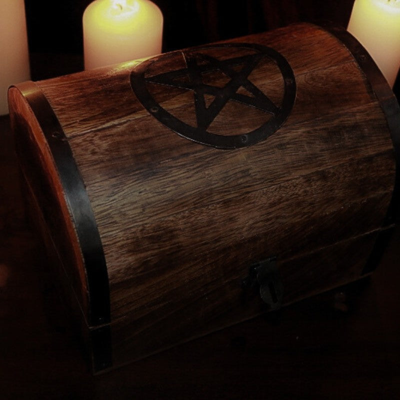 Rustic Wooden Chest with black metal Pentacle on top in front of  lit beeswax candles