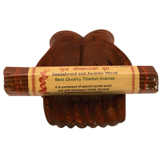 pk of hand rolled "sandalwood and jasmine" tibetan incense sitting on a statue of carved wooden hands