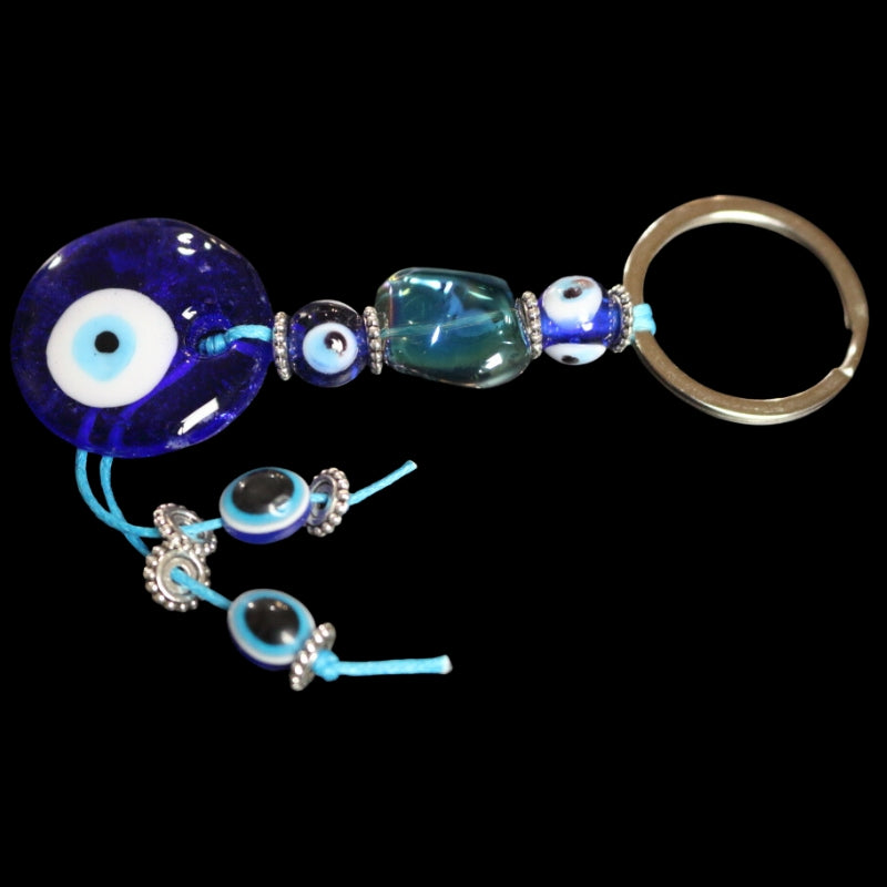 silver key ring attached to a blue cord, with a string of a blue beads with white, light blue and black centres, on a black background