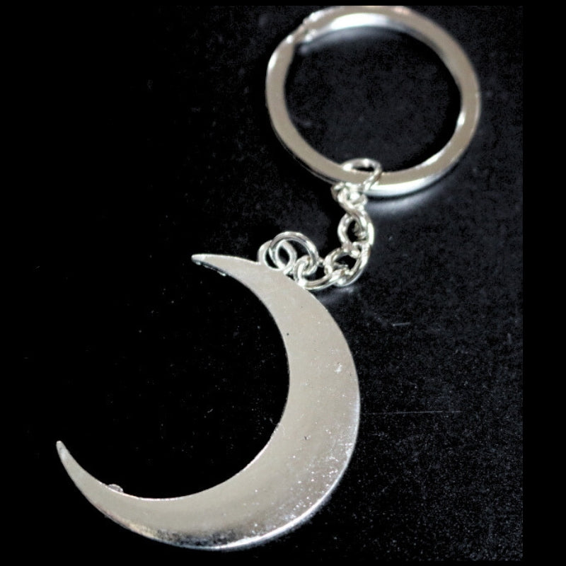 silver coloured key ring with a crescent moon  joined to a silver ring by a silver chain on a black background