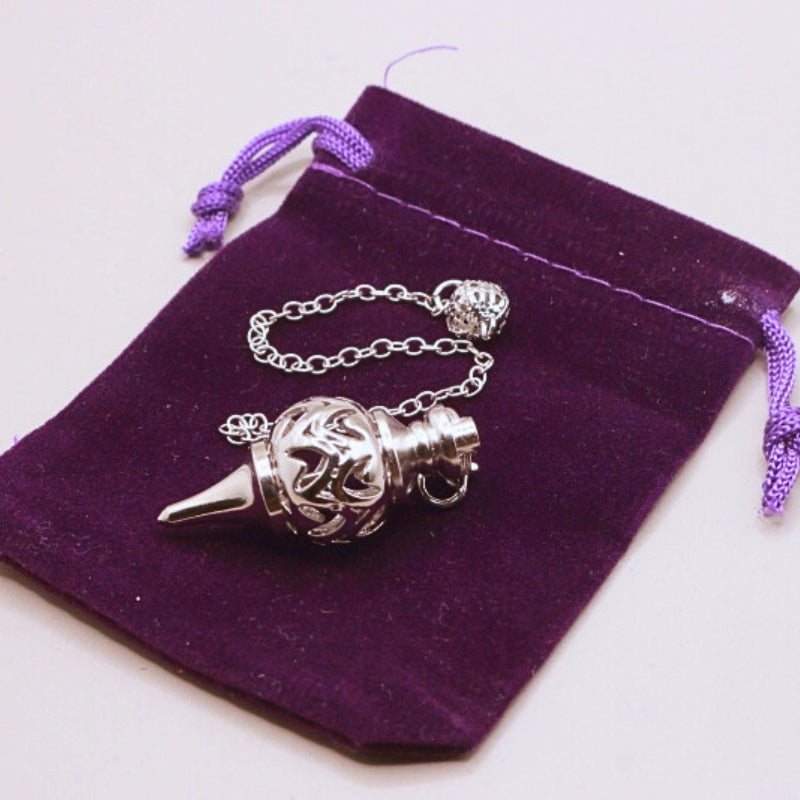 silver pendulum on purple velvet bag