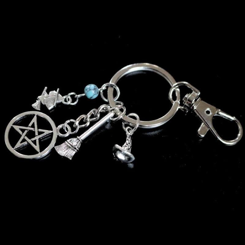 silver coloured key ring with a pentacle (5 pointed star within a circle) , a witch riding a broomstick, a witches hat and a broom joined to a silver ring by a silver chain. The keyring has a silver hook attached to the ring