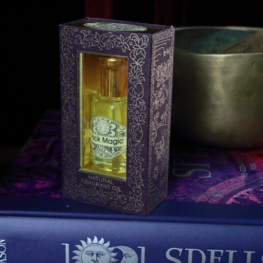 Black Magic Song of India Perfume Oil sitting on a book of spells in front of a singing bowl