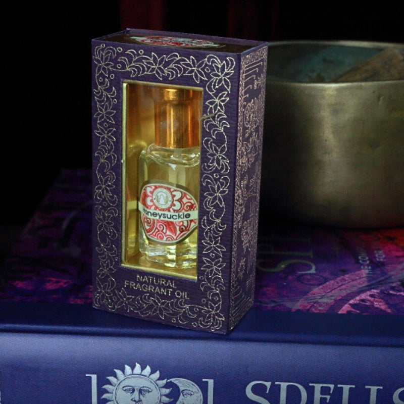 Honeysuckle Song of India Perfume Oil sitting on a book of spells in front of a singing bowl