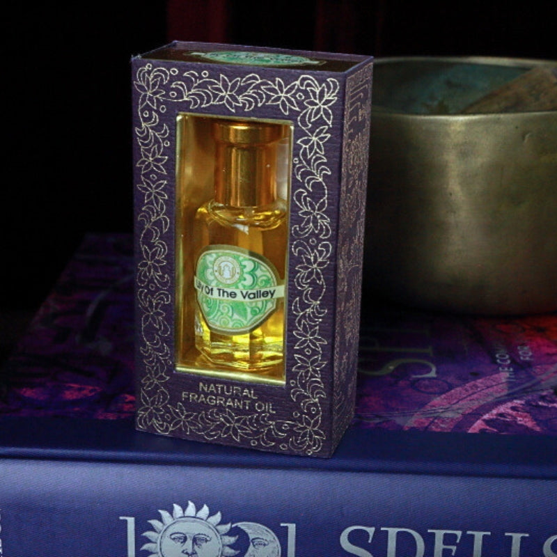 Lily Of The Valley Song of India Perfume Oil sitting on a book of spells in front of a singing bowl