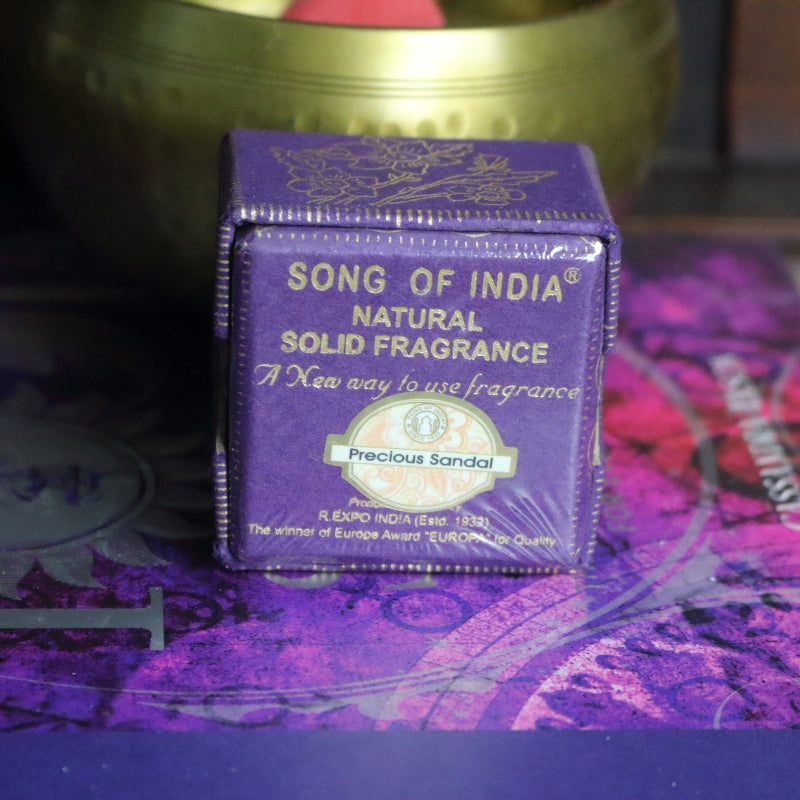 purple and gold box  sitting on a purple and pink book of spells in front of a brass singing bowl with wooden striker.