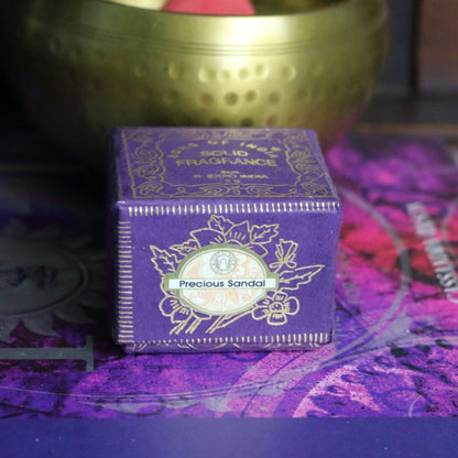 purple and gold box , sitting on a purple and pink book of spells in front of a brass singing bowl with wooden striker.