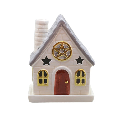 A small decorative house-shaped ceramic container or figurine with a white brick-textured body, gray roof, red-brown door, gold window trim and pentagram emblem, plus black stars, shown on a plain white background.