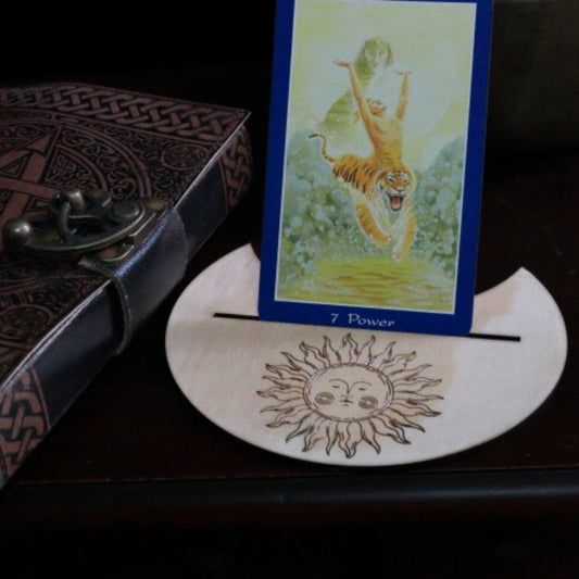Handmade Sun Tarot Card Holder holding a tarot card, next to a pentacle journal