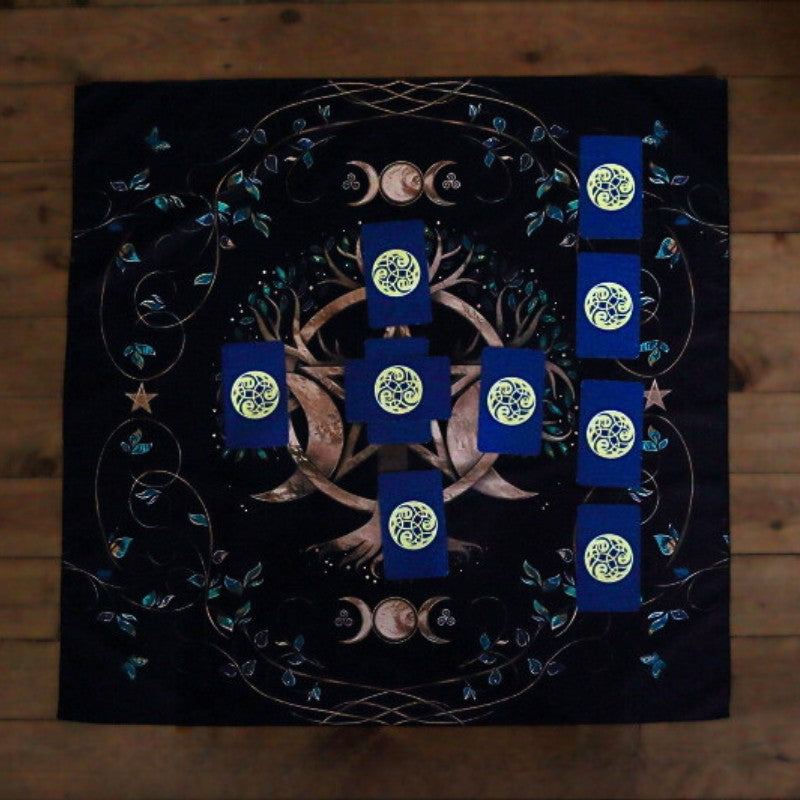 celtic cross spread laid out on a black tarot cloth with a triple moon pentacle design and tree