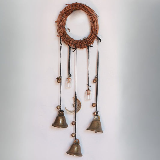 Decorative wall hanging with bronze bells and a woven top section on a light gray background
