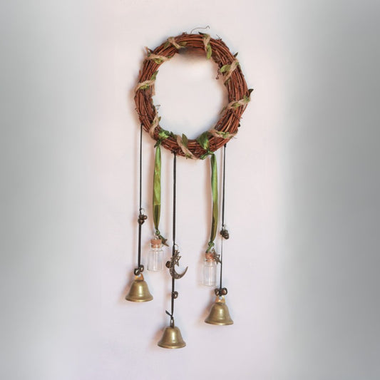 Decorative wall hanging with a vine wreath and hanging bells on a plain background