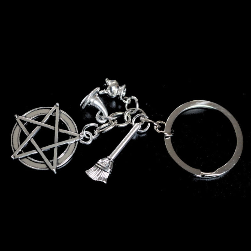 silver coloured key ring with a pentacle (5 pointed star within a circle) , a cauldron , a witches hat and a broom joined to a silver ring by a silver chain. 