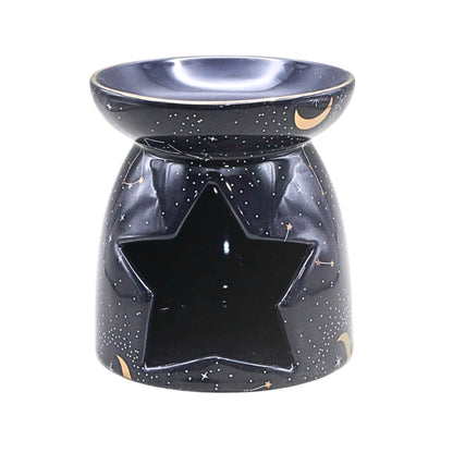 A ceramic oil burner and candle holder with a star-shaped cutout on the front, decorated with a black starry sky pattern and small gold crescent moon accents, shown on a plain white background.