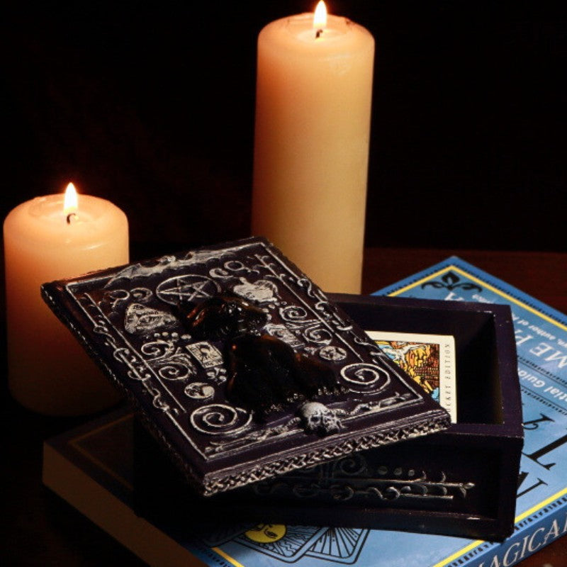 Black Cat Tarot Card Storage Box with a pack of pocket sized rider waite tarot cards in front of beeswax candles on a tarot book