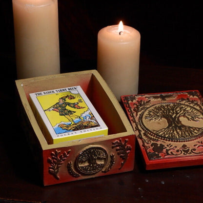 tree of life Tarot Card Storage Box with a pack of pocket sized rider waite tarot cards in front of beeswax candles on a tarot book