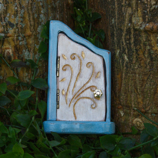 blue and white wooden door for fairies with a gold door handle and hinges