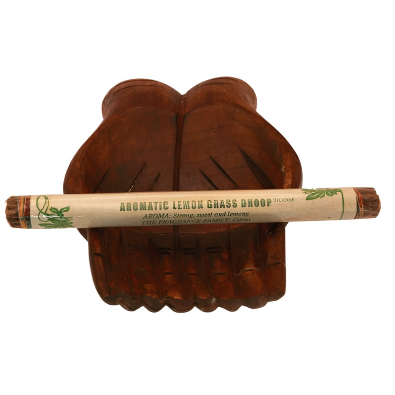 pk of hand rolled tibetan incense sitting on a statue of carved wooden hands