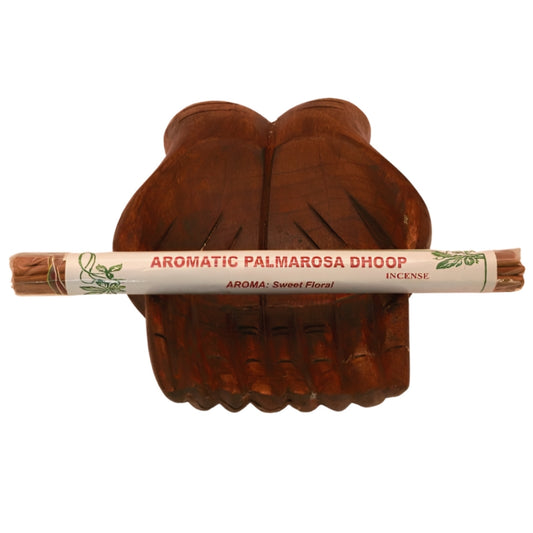 pk of hand rolled  tibetan incense sitting on a statue of carved wooden hands