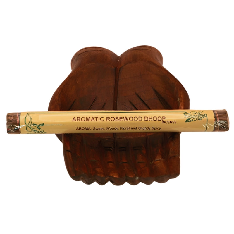pk of hand rolled tibetan incense sitting on a statue of carved wooden hands