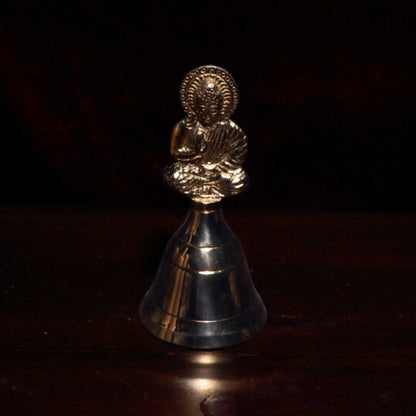 brass bell with buddha on handle on wooden altar