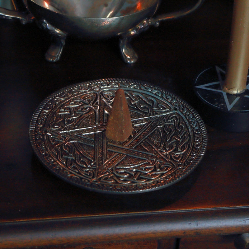 incense cone sitting on an aluminium incense holder with a celtic pentacle design