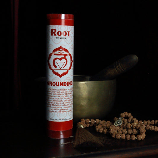 Red Root chakra pillar candle in front of a singing bowl with mala beads