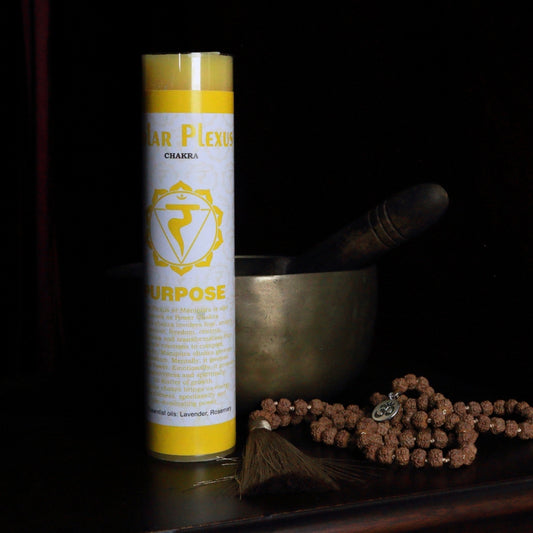 yellow solar plexus chakra pillar candle in front of a singing bowl with mala beads