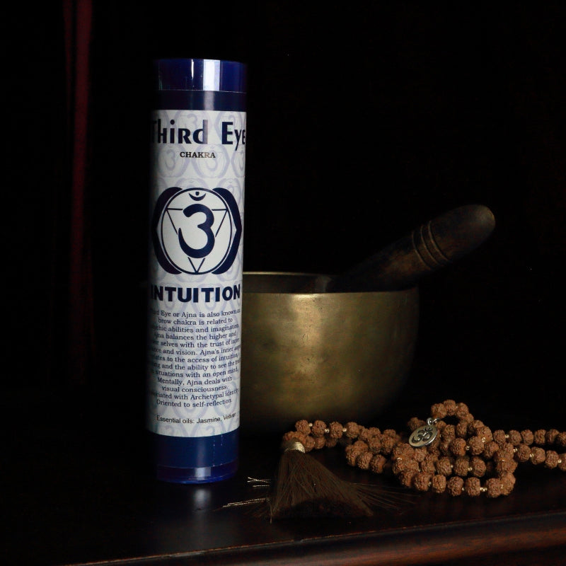 indigo Third eye  chakra pillar candle in front of a singing bowl with mala beads