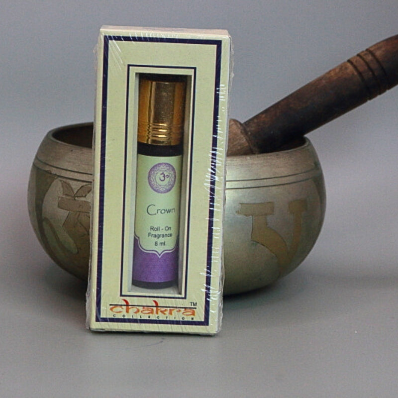 Crown chakra roll on perfume oil sitting in front of a singing bowl