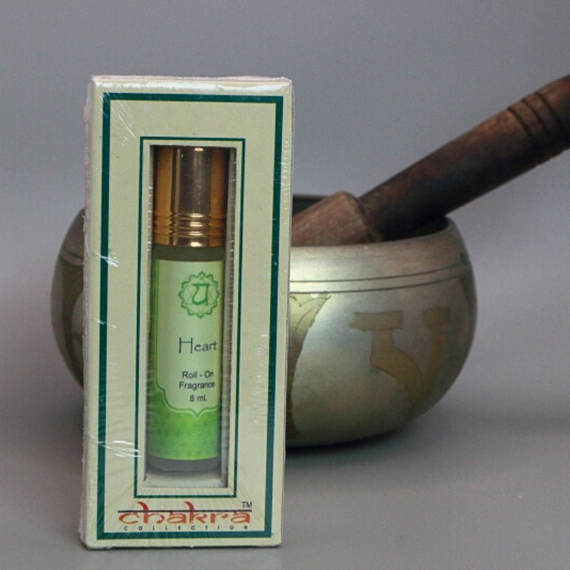 Heart chakra roll on perfume oil sitting in front of a singing bowl