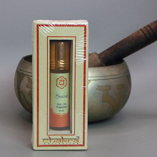 sacral chakra roll on perfume oil sitting in front of a singing bowl