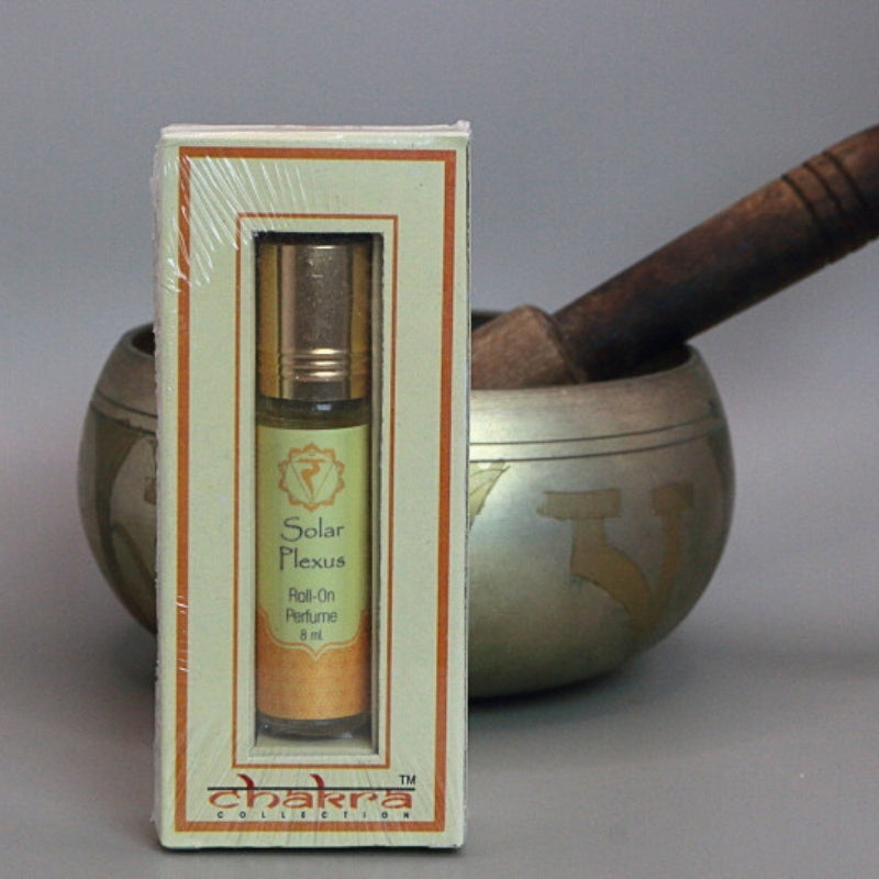Solar plexus chakra roll on perfume oil sitting in front of a singing bowl