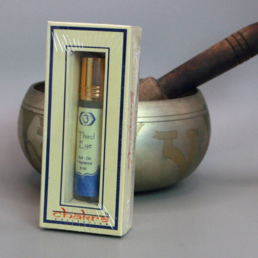 Third Eye chakra roll on perfume oil sitting in front of a singing bowl