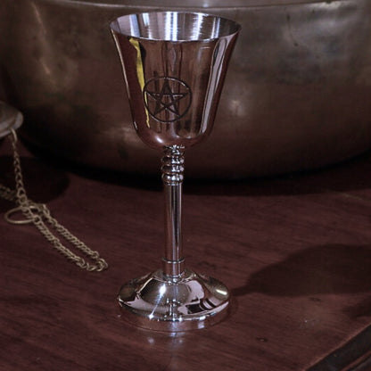 Silver goblet with a pentagram symbol on a wooden surface